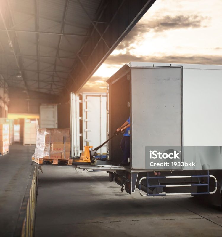 istockphoto-1325350394-2048×2048 Package Boxes on Pallets Loading into Cargo Container. Trucks Parked Loading at Dock Warehouse. Delivery Service. Shipping Warehouse Logistics. Road Freight Truck Transportation.